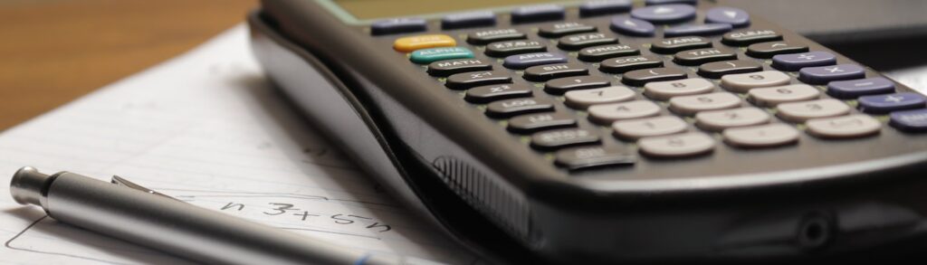 Calculadora sobre folha de papel com anotações e caneta, representando o cálculo do ponto de equilíbrio de uma empresa