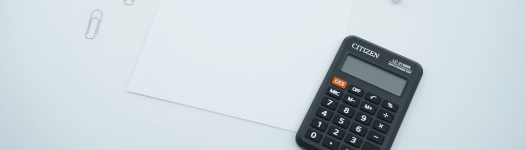 Calculadora e papel em branco sobre mesa, representando o calculo da folha de pagamento