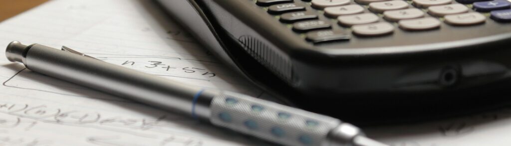 Calculadora científica e caneta sobre caderno com anotações, representando o cálculo do sublimite do Simples Nacional