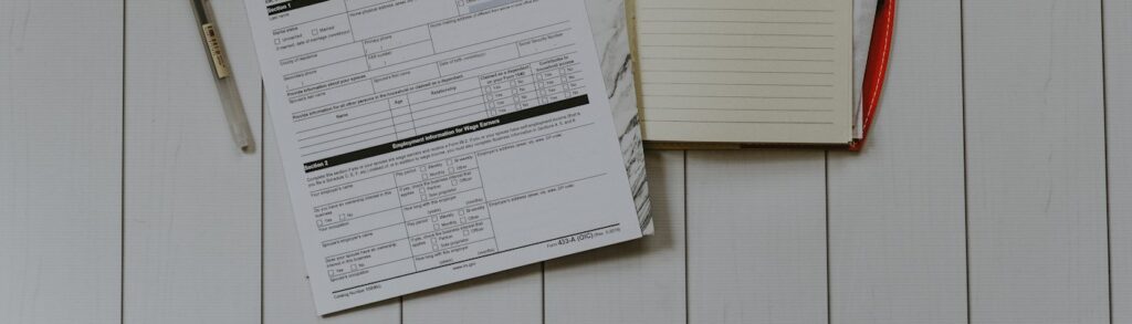 Formulário fiscal, caderno e caneta sobre mesa de madeira clara