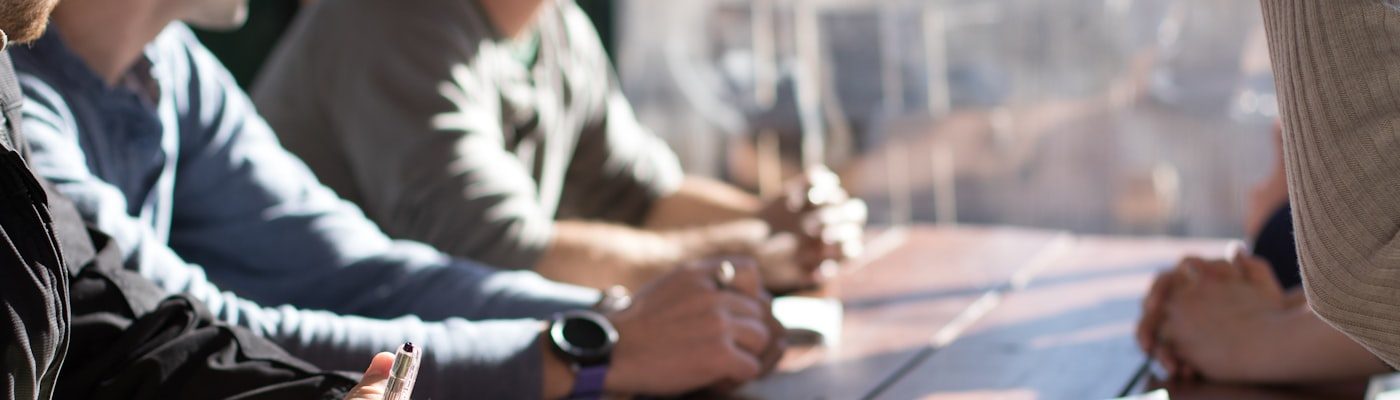 Pequena equipe reunida em volta de uma mesa, anotando e conversando durante uma reunião de planejamento