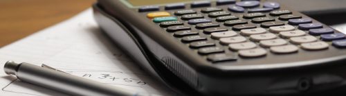Calculadora sobre folha de papel com anotações e caneta, representando o cálculo do ponto de equilíbrio de uma empresa