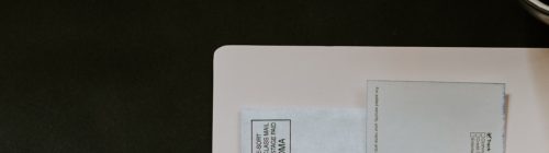 Celular, caneta e documento fiscal sobre uma pasta branca, compondo uma cena de organização financeira